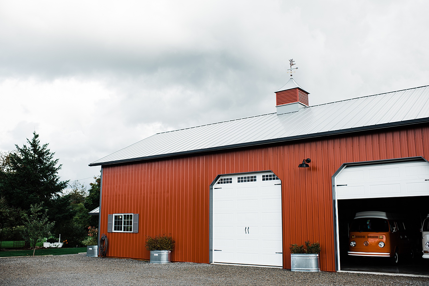a Burgundy red color barn with huge white door in a cloudy day