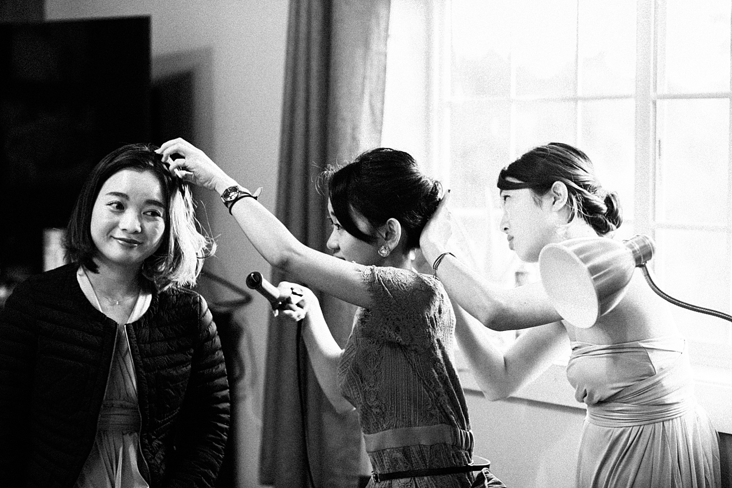 three bridesmaids are helping each other with hair style