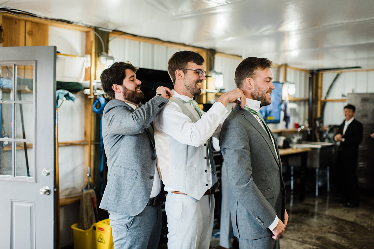 a groom is getting helped getting ready from other best men while himself is in the middle