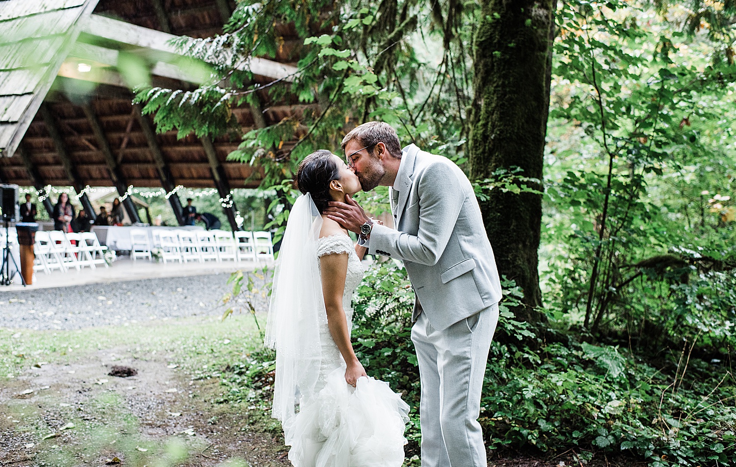 a groom is holding his bride's face while kissing her after their first look