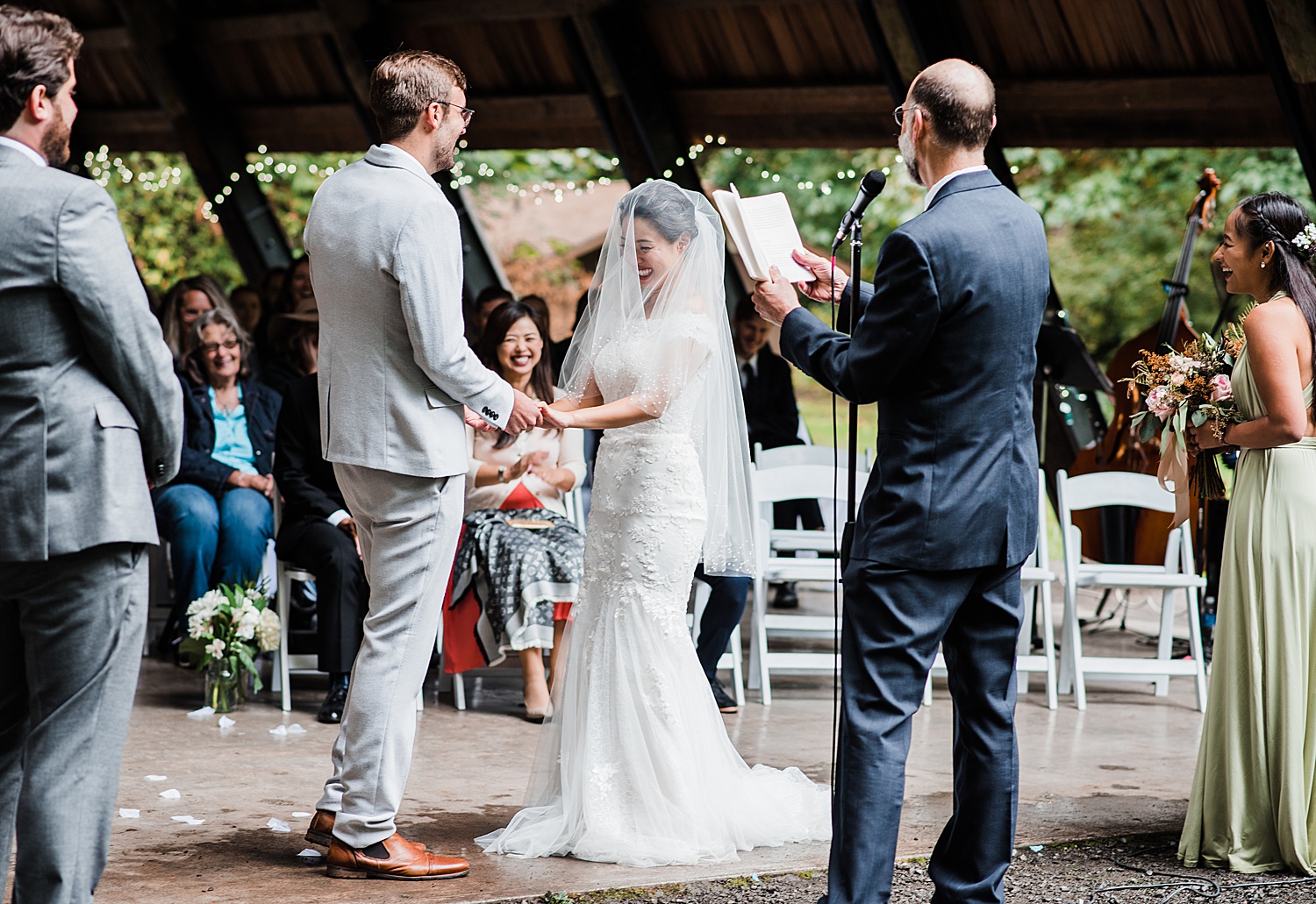 a bride and a groom are holding hands while laughing at each other by a joke made by officiant